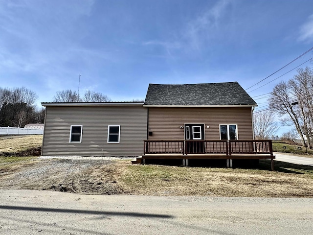 back of property with a shingled roof and a deck