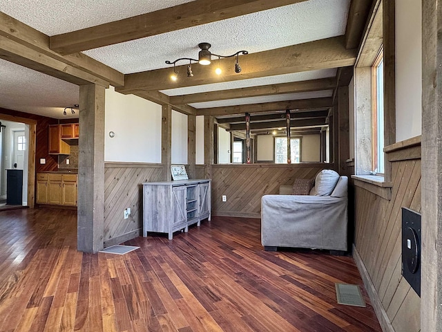 sitting room with wood walls, visible vents, hardwood / wood-style flooring, and a textured ceiling
