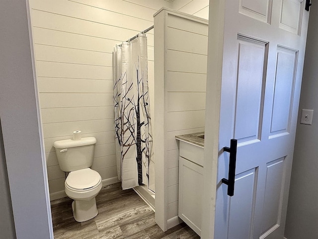 full bathroom featuring toilet, a stall shower, and wood finished floors