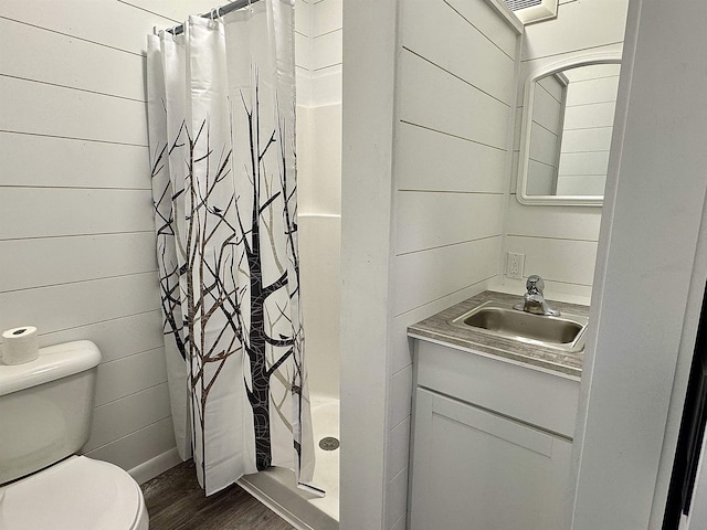 bathroom featuring visible vents, toilet, a shower stall, vanity, and wood finished floors