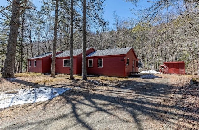 view of property exterior with a view of trees and driveway