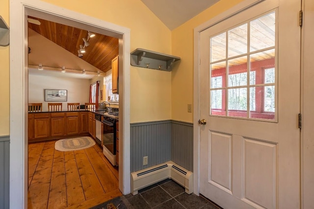 entryway featuring a sink, wood ceiling, baseboard heating, vaulted ceiling, and a wainscoted wall