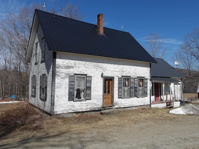 back of property with metal roof and a chimney