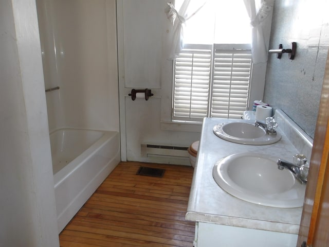 bathroom featuring double vanity, baseboard heating, hardwood / wood-style flooring, and a sink