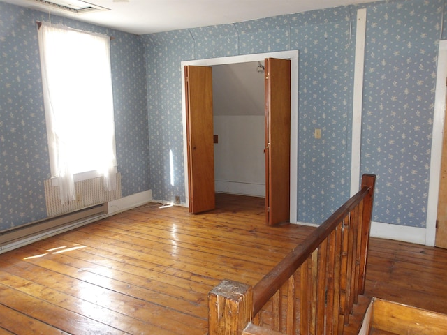 spare room with hardwood / wood-style flooring and wallpapered walls
