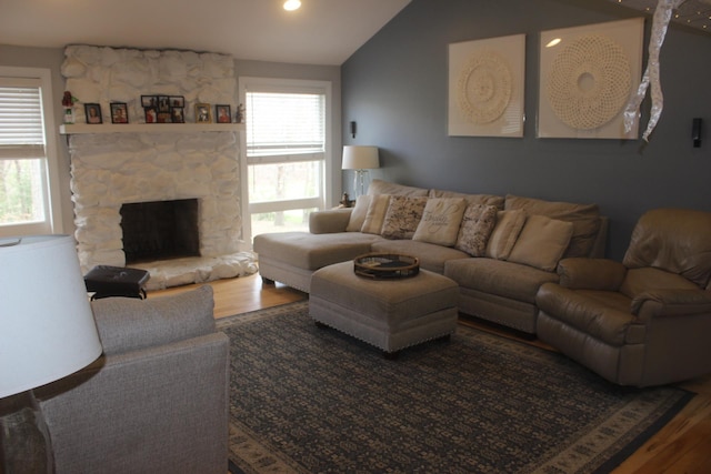 living room with wood finished floors, lofted ceiling, and a fireplace