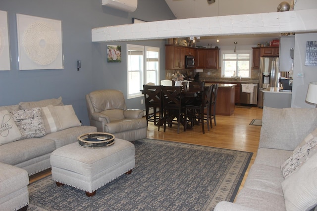 living area with a wall mounted AC and light wood-style flooring