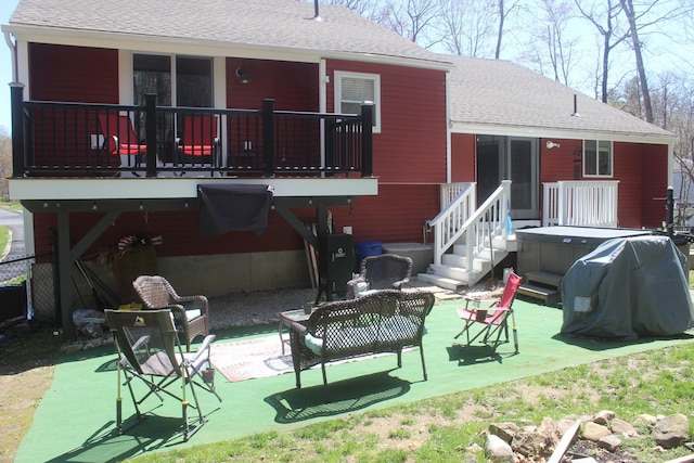 back of property featuring a patio, a hot tub, and roof with shingles