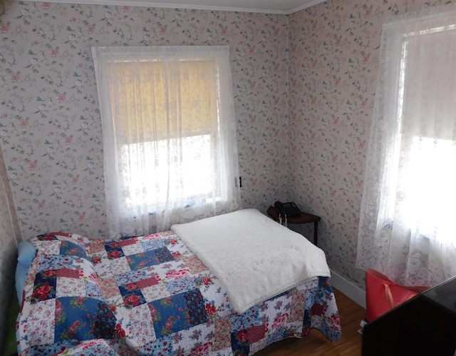 bedroom with wood finished floors and wallpapered walls
