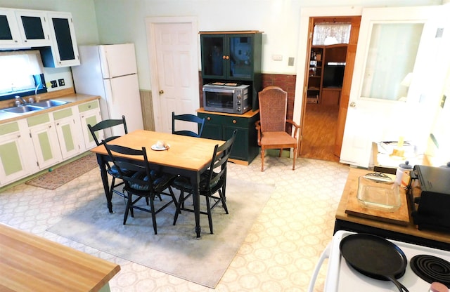 dining space featuring a toaster, a wainscoted wall, and light floors
