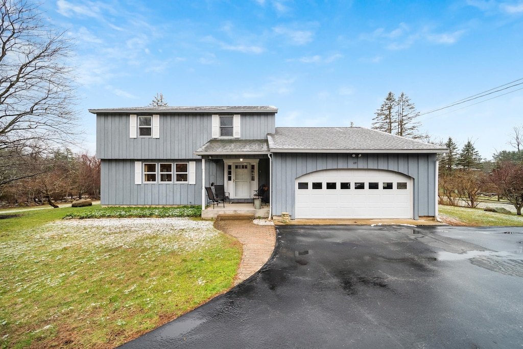 view of front of house featuring roof with shingles, a front lawn, a garage, and aphalt driveway