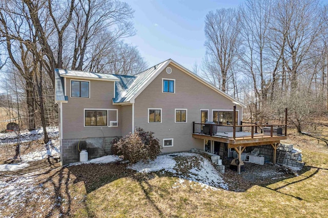 snow covered back of property with a yard, metal roof, and a deck