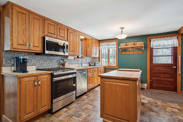kitchen with tasteful backsplash, a sink, butcher block counters, stainless steel appliances, and a baseboard heating unit