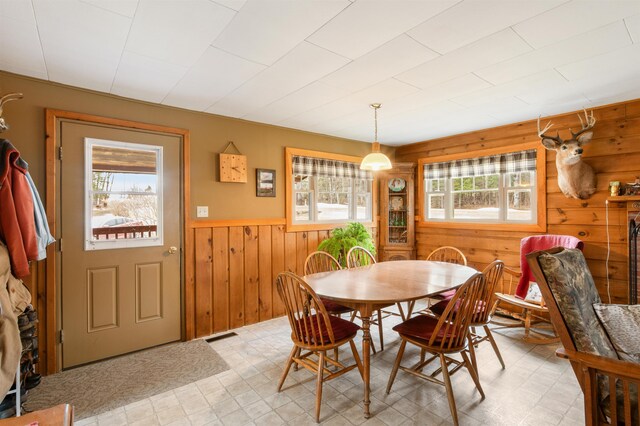 dining room with wooden walls, a wainscoted wall, and light floors