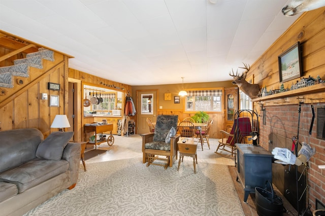 living room featuring wood walls, stairs, and a wood stove