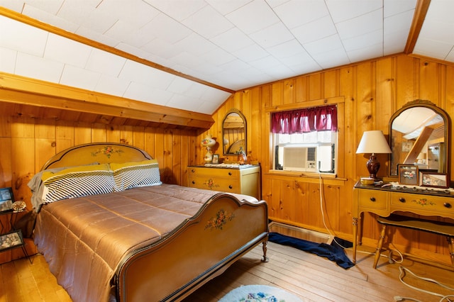 bedroom featuring wooden walls, light wood-type flooring, and vaulted ceiling