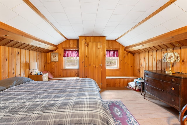bedroom featuring wooden walls, light wood-style floors, and lofted ceiling