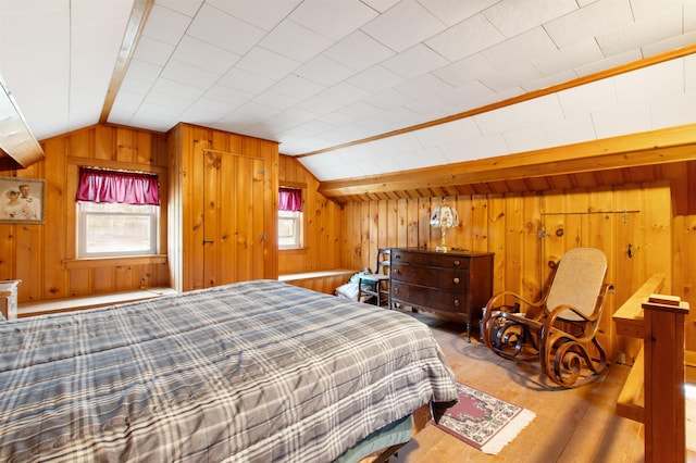 bedroom featuring wooden walls, wood finished floors, and lofted ceiling