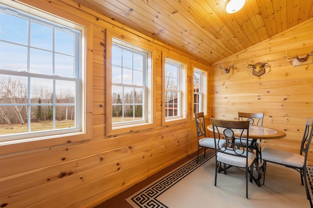 dining area with wood walls, wooden ceiling, and vaulted ceiling