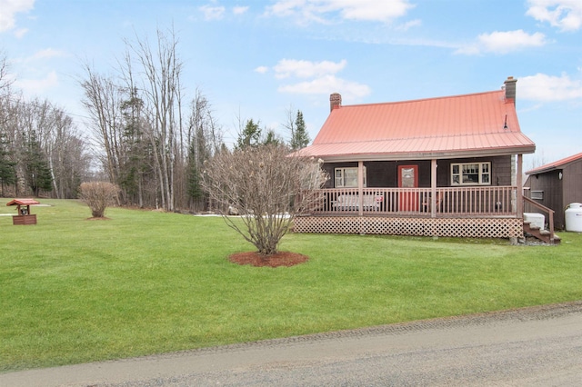 view of front of home with a front yard, a porch, a chimney, and metal roof