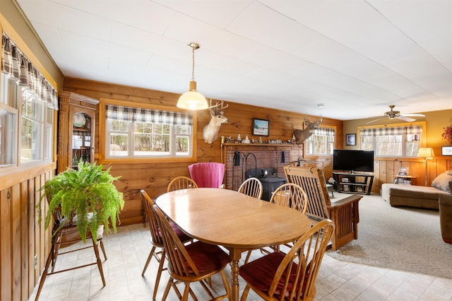 dining space featuring wood walls, a ceiling fan, and light floors