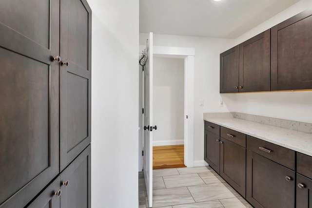 12 Wildwood Rd, Gilford, NH 03249 - kitchen featuring dark brown cabinets, baseboards, marble finish floor, and light stone counters