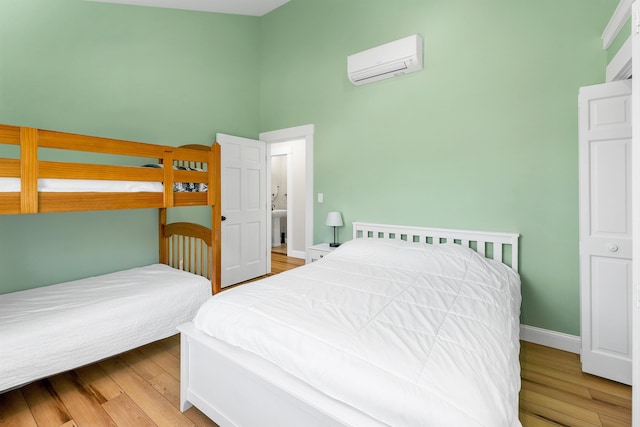 12 Wildwood Rd, Gilford, NH 03249 - bedroom with wood finished floors, a towering ceiling, an AC wall unit, and baseboards