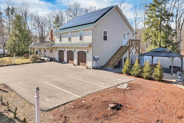 12 Wildwood Rd, Gilford, NH 03249 - rear view of property with stairway, an attached garage, solar panels, a gazebo, and metal roof