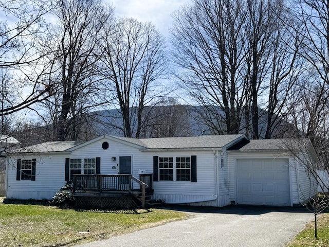 single story home featuring aphalt driveway, a shingled roof, a wooden deck, and an attached garage