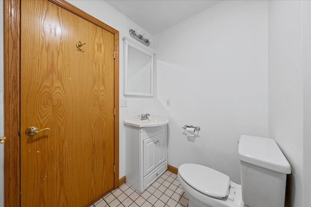 half bathroom with vanity, baseboards, and toilet