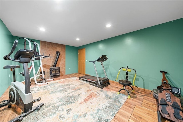 workout area with wood finished floors, a wood stove, and recessed lighting