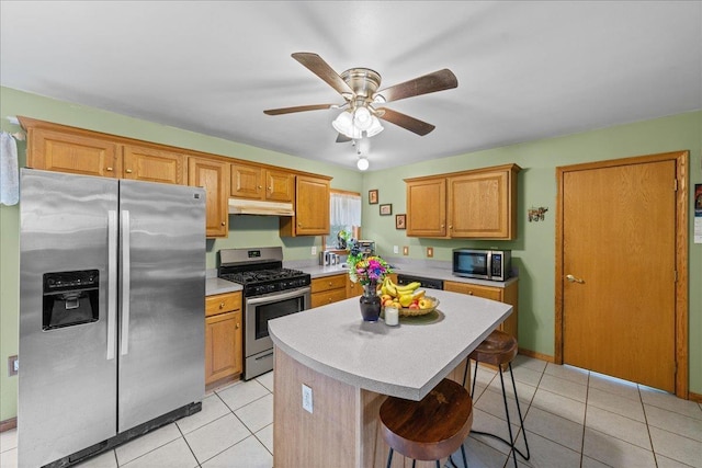 kitchen featuring a kitchen bar, a center island, under cabinet range hood, light countertops, and stainless steel appliances