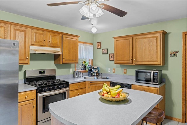 kitchen featuring ceiling fan, under cabinet range hood, light countertops, a sink, and stainless steel appliances