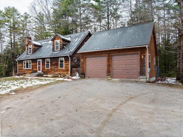 view of front facade featuring aphalt driveway, a chimney, and an attached garage