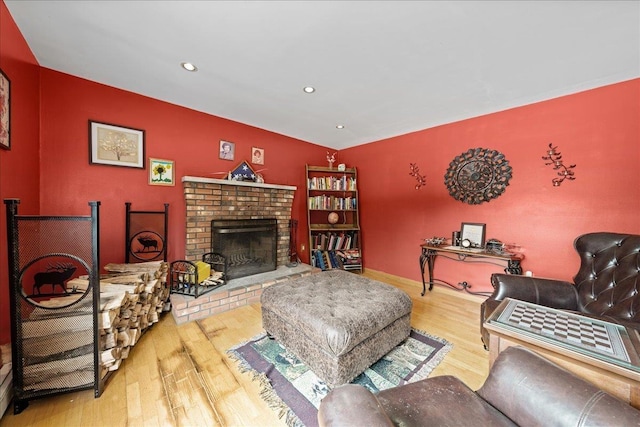 living room featuring recessed lighting, a brick fireplace, and wood finished floors