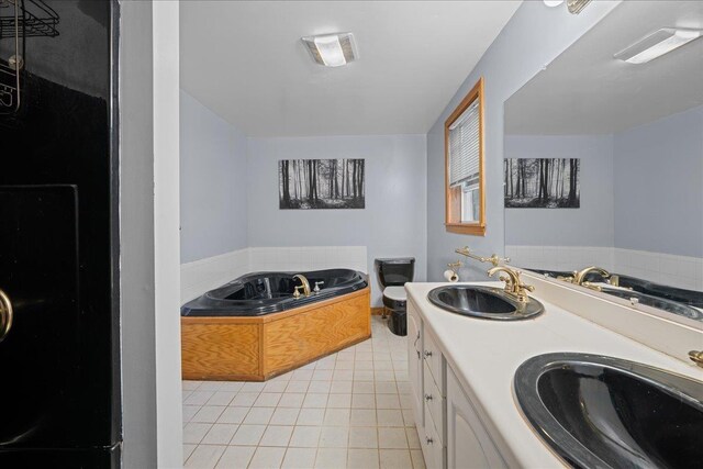 bathroom with tile patterned floors, a garden tub, double vanity, and a sink