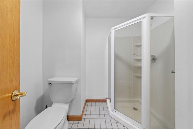 full bathroom with a shower stall, tile patterned floors, baseboards, and toilet