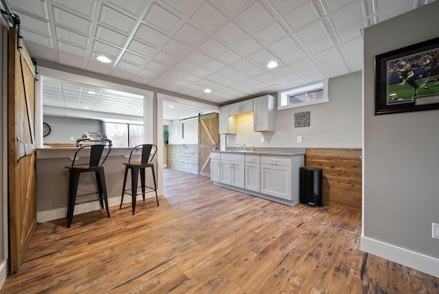 kitchen featuring baseboards, recessed lighting, a barn door, and light wood-style floors