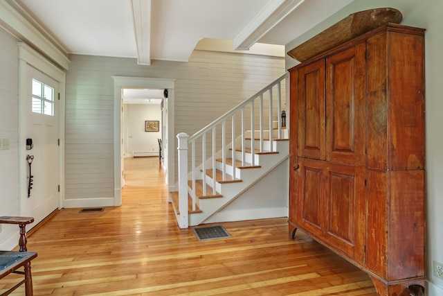 foyer entrance featuring stairs, visible vents, beamed ceiling, light wood finished floors, and a baseboard radiator