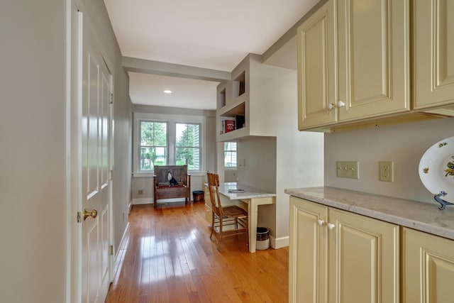 kitchen featuring cream cabinetry, baseboards, open shelves, and light wood finished floors