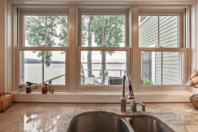 room details with a water view, a sink, and light stone counters