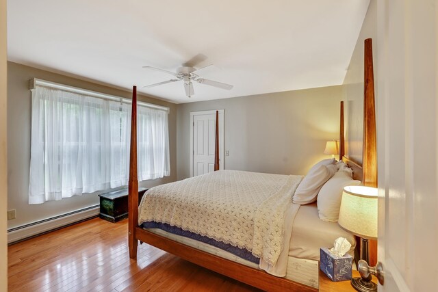 bedroom featuring ceiling fan, hardwood / wood-style floors, and a baseboard heating unit