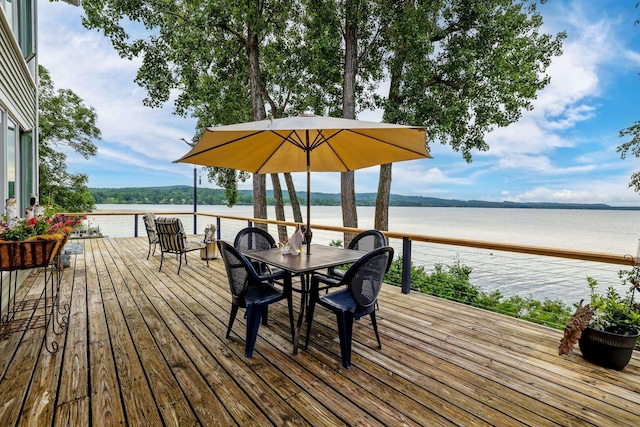 deck with a water view and outdoor dining area