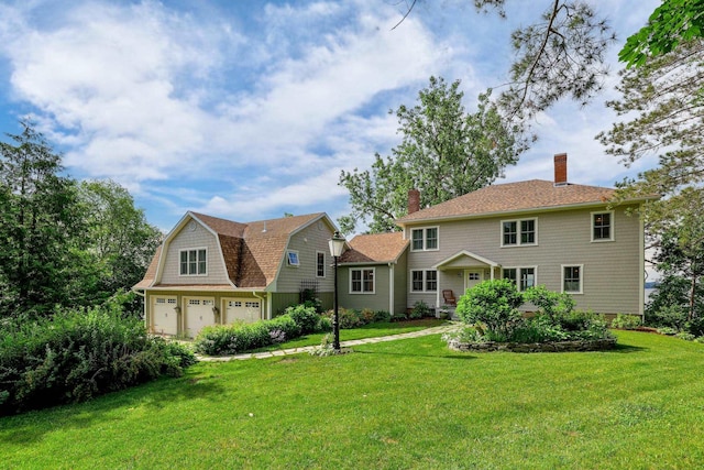 view of front of home featuring an attached garage, a chimney, and a front lawn