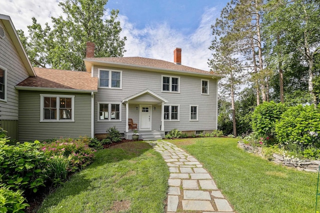 colonial inspired home featuring a chimney and a front lawn