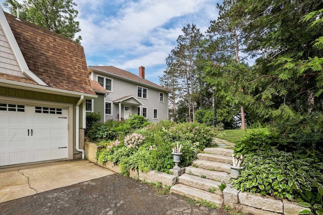 exterior space featuring roof with shingles, driveway, and a garage