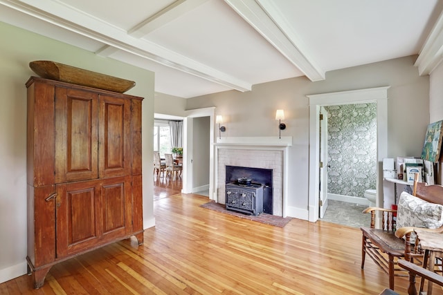 living room featuring light wood finished floors, beamed ceiling, and baseboards