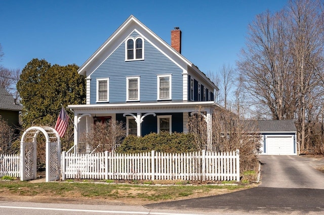 farmhouse featuring a chimney, covered porch, and a fenced front yard
