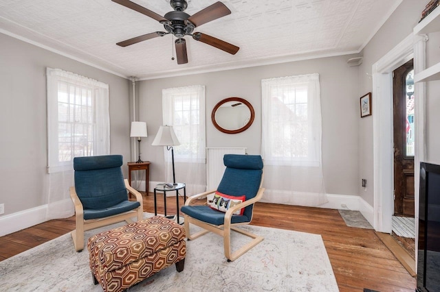 sitting room featuring crown molding, wood finished floors, a ceiling fan, and a wealth of natural light