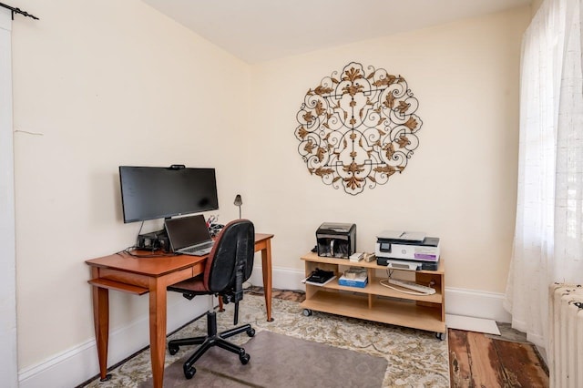 office area featuring wood finished floors, radiator heating unit, and baseboards